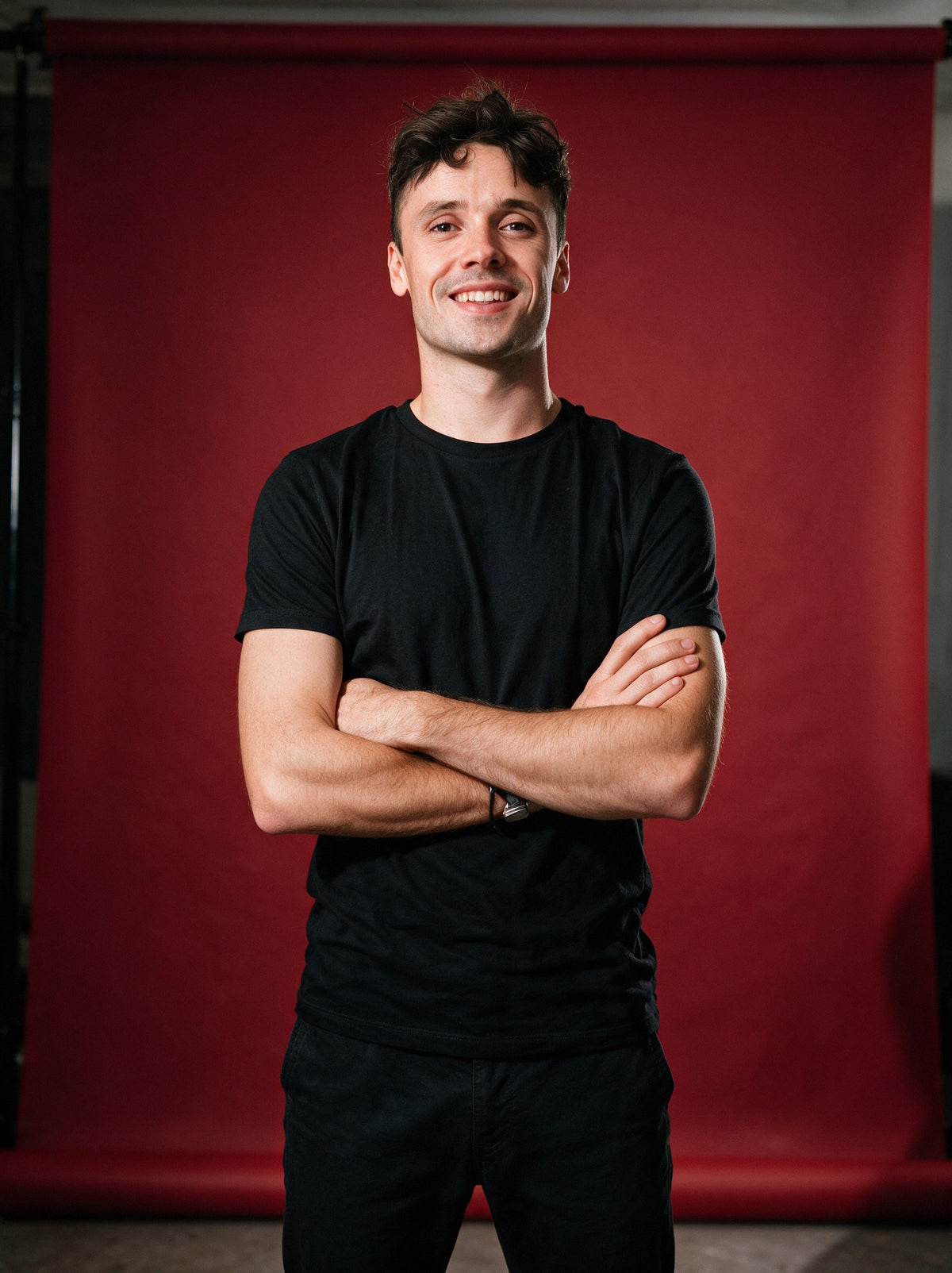 Aurélien, founder of Scalypin, arms crossed against a deep red studio backdrop