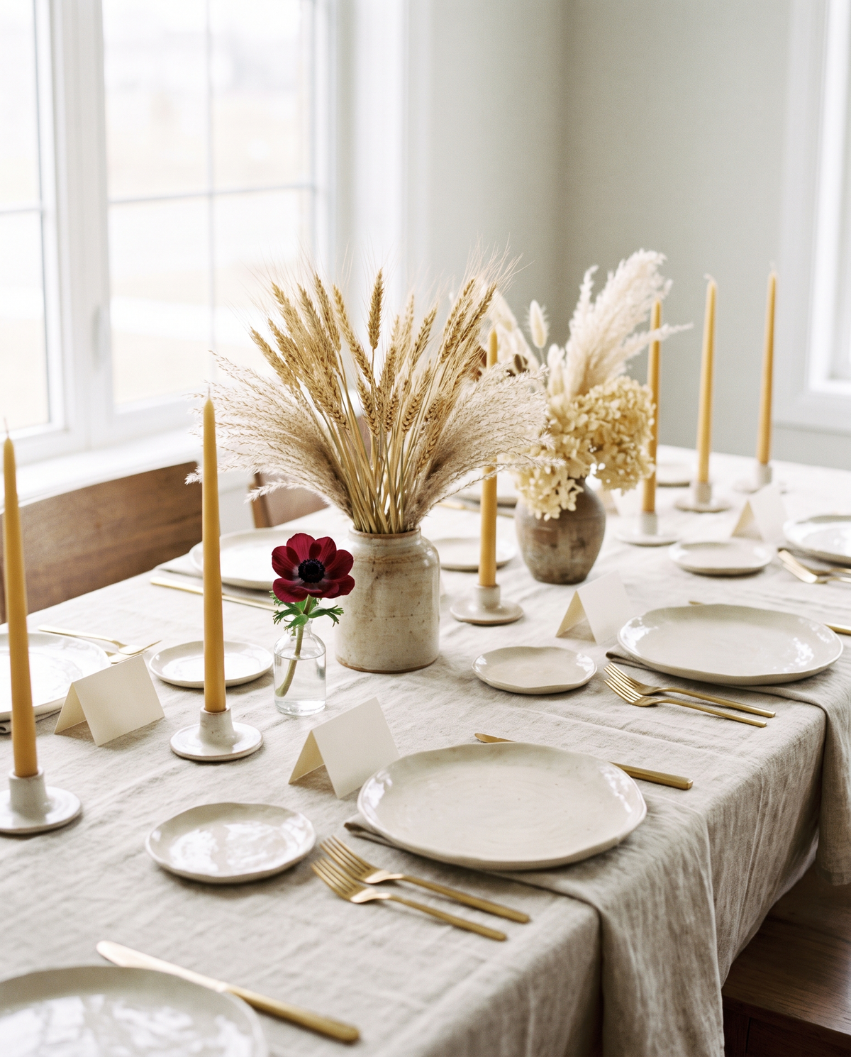 Wedding table with linen, ceramic plates, candles and a single red flower